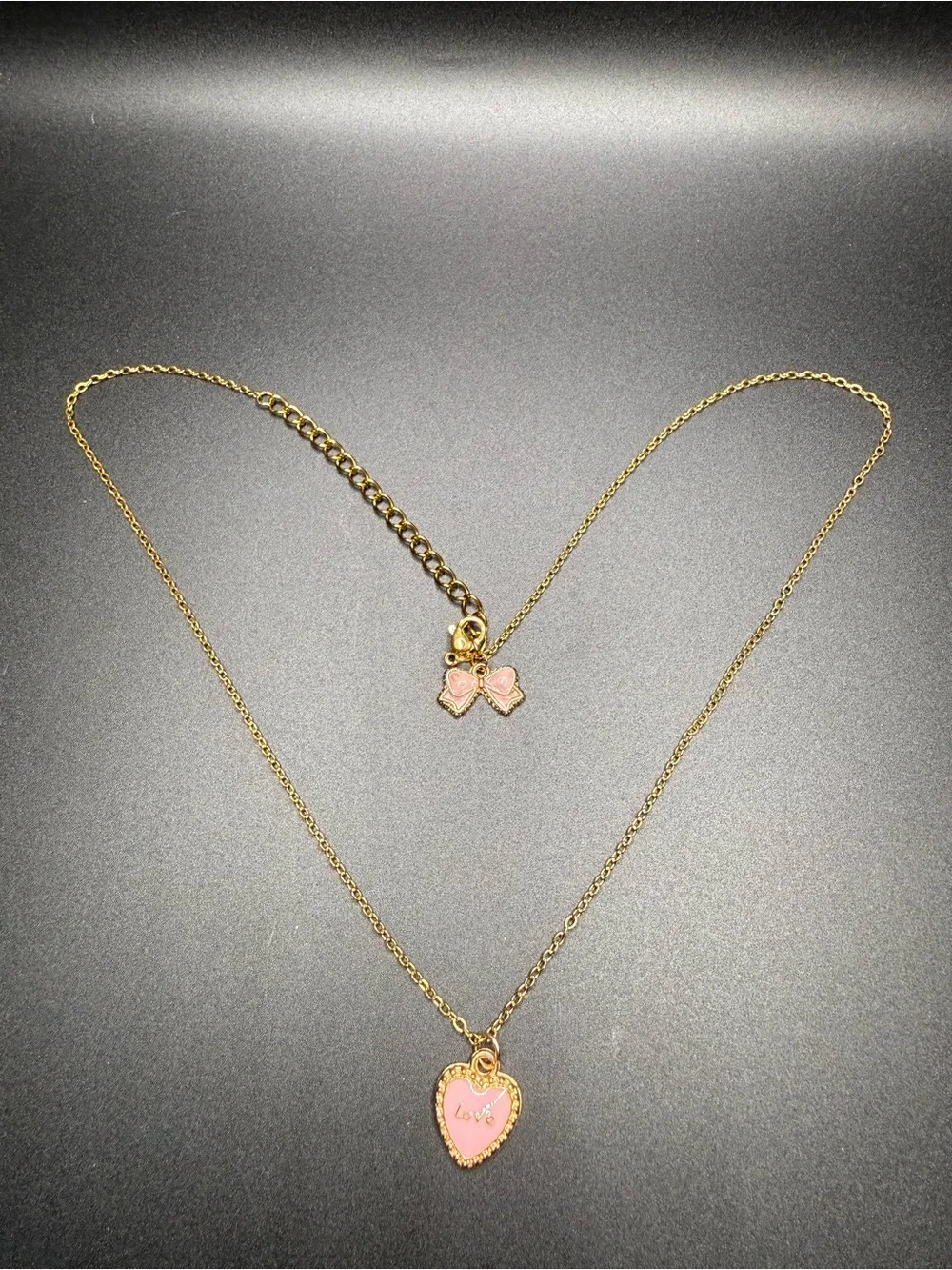 Gold-Tone Necklace with Pink Heart Pendant and bow at the end.